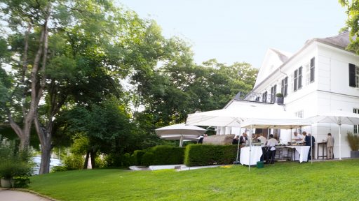 Elegantes Gartenfest bei einem weißen Haus mit Gästen im Freien.