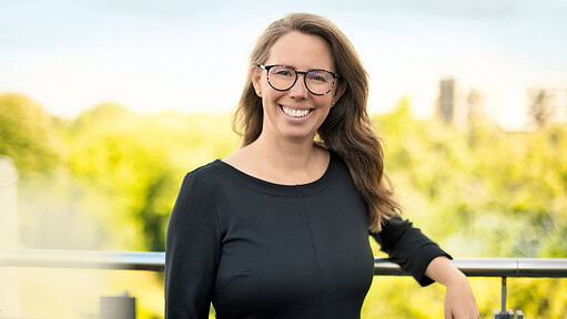 Lächelnde Frau mit Brille vor grünem Hintergrund bei Berufsbildung.