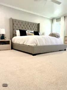 Bedroom with light-colored carpet, upholstered bed, and neutral walls