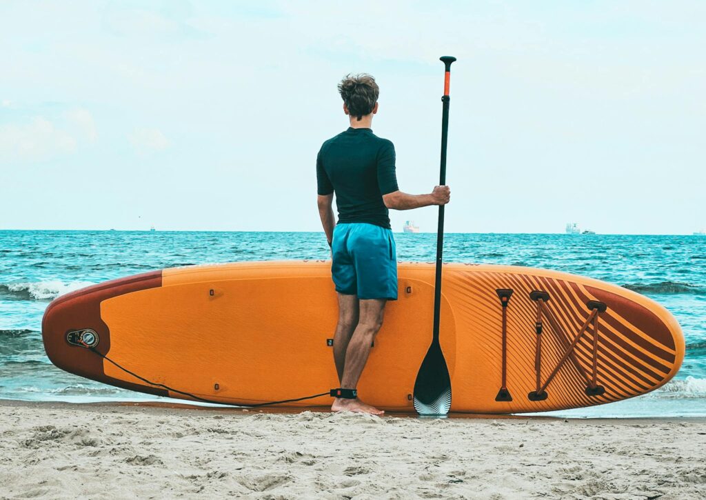 Mastering the Waves: How to Choose a Paddleboard 2 Man with Paddle Board on the Beach