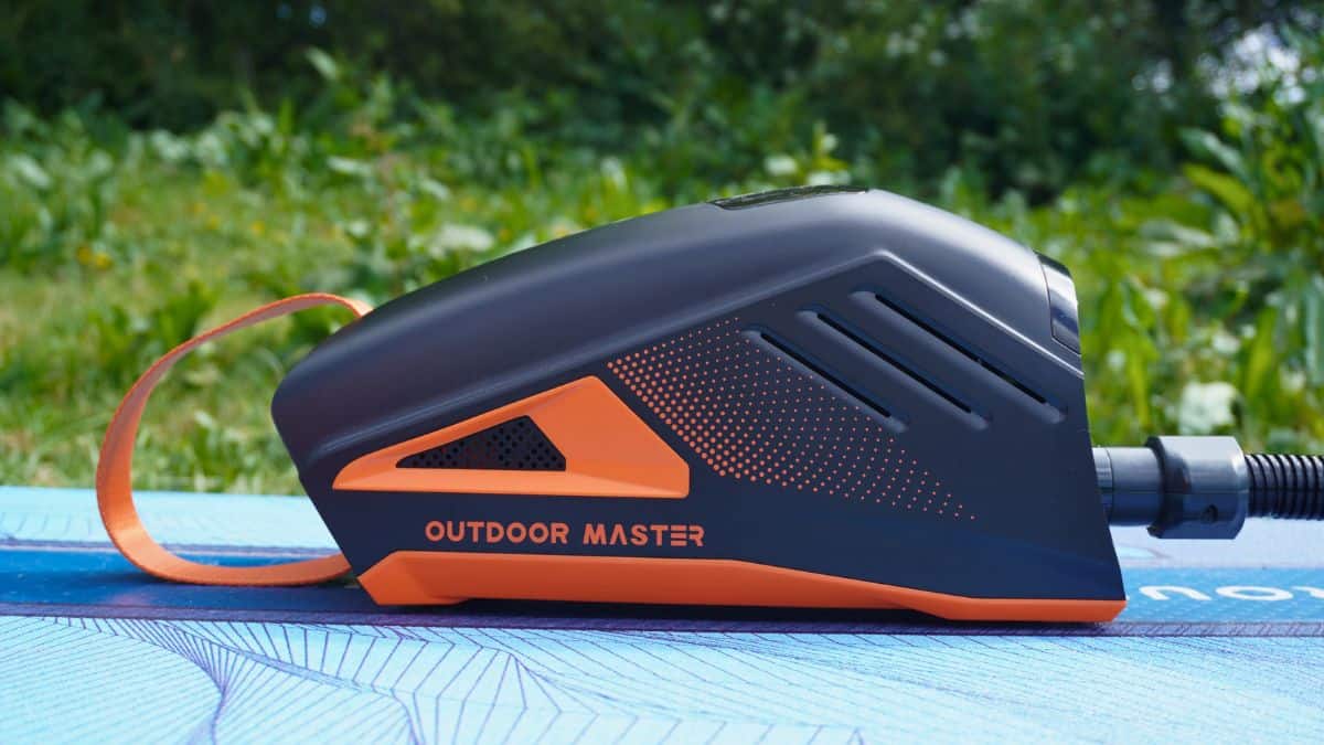 Outdoor Master Shark 3 electric pump in black and orange, resting on a paddleboard outdoors
