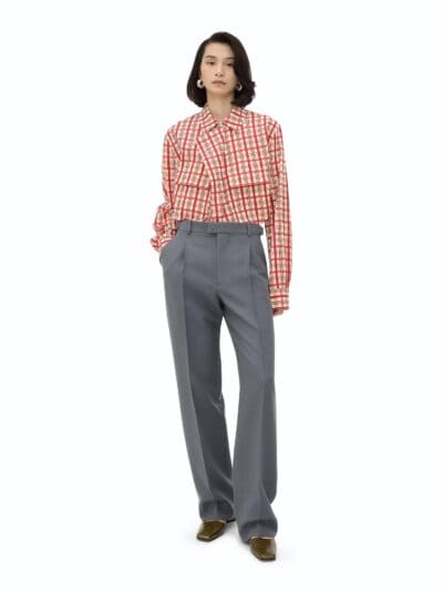 Blusa de xadrez vermelha com detalhes clássicos, combinada com calças cinza elegantes e sapatos de couro.