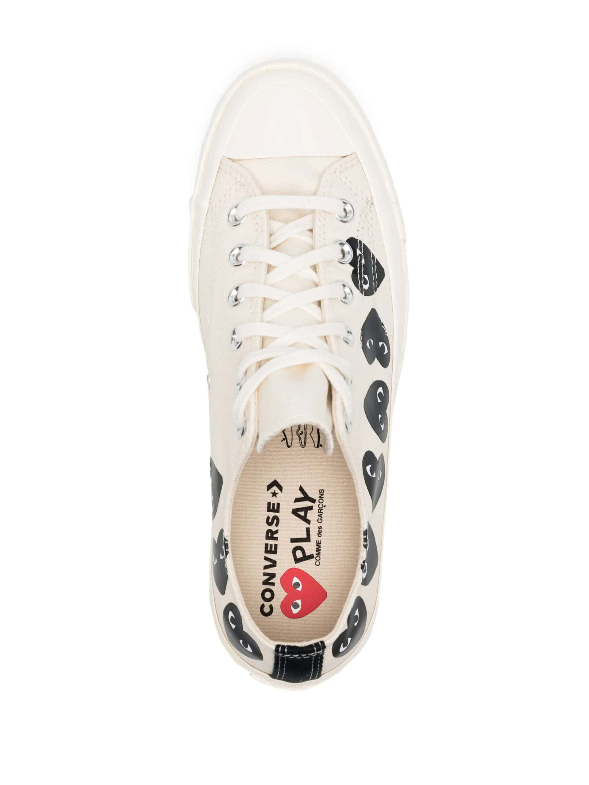 Converse Chuck Taylor All Star em bege com detalhes de corações pretos e vermelhos.