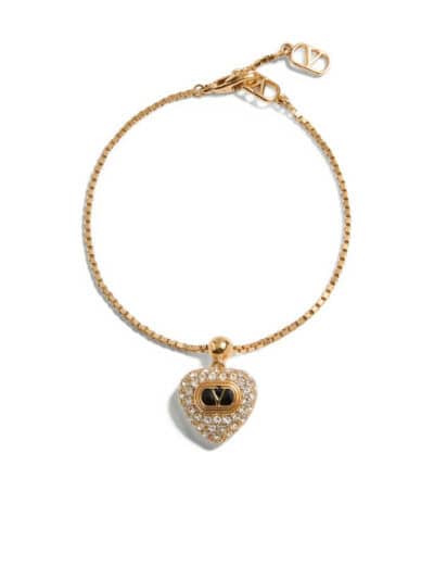 Pulseira de ouro com pingente de coração adornado com pedras preciosas e logotipo da marca. Acessório elegante e sofisticado.