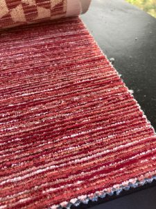 Vloerkleed met rode tinten en textuurrijke afwerking, perfect voor interieurdecoratie en sfeerverbetering.