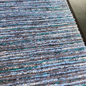 Alt tekst: Gevlochten stoffen met blauw, grijs en groen tinten, ideaal voor interieurdecoratie.