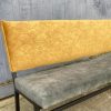 Alt tekst: Zwart metalen bank met gele, gestoffeerde rugleuning en zachte bekleding, geschikt voor interieurdecoratie.