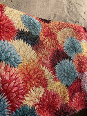 Textielstoffencollectie, kleurrijk interieurstof met bloemmotief, kwalitatieve stoffen voor decoratie. Alt tekst: Diverse gekleurde bloemmotieven op een stoffenbank, perfect voor interieurdecoratie.