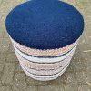 Een rond, blauw vloerkleed met een rijke textuur op een stenen vloer buiten.