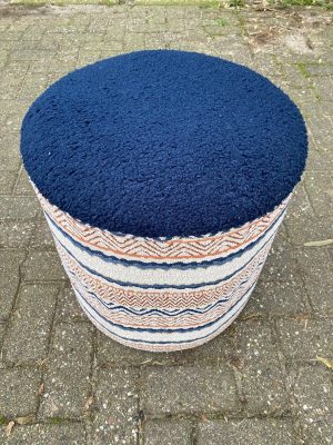Een rond, blauw vloerkleed met een rijke textuur op een stenen vloer buiten.