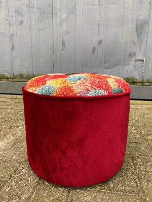 Gemonteerde fauteuil of poef met bloemmotief en rode bekleding.