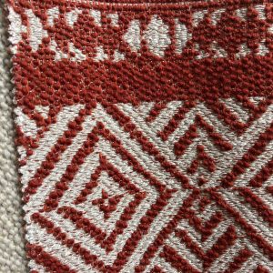 Decoratieve stof met rood en wit geometrisch design voor moderne interieurs.