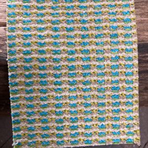 Vrolijk gekleurd tapijt met blauw, groen en beige tinten voor een levendige sfeer.