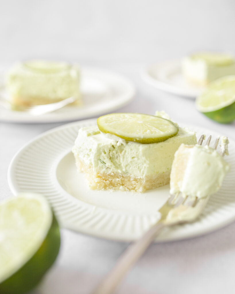 No Bake Key Lime Bar cut on a plate with one forkful taken out of it.