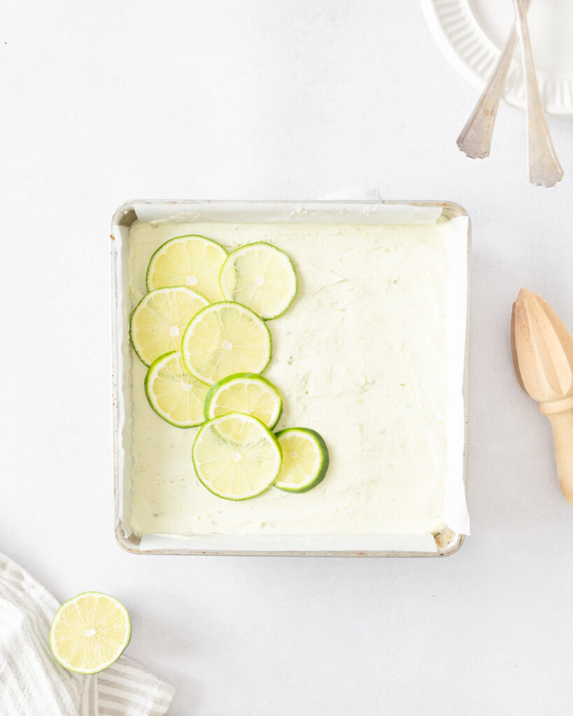 Gluten Free Key Lime Cheesecake Bars set in a square pan and decorated with lime slices.