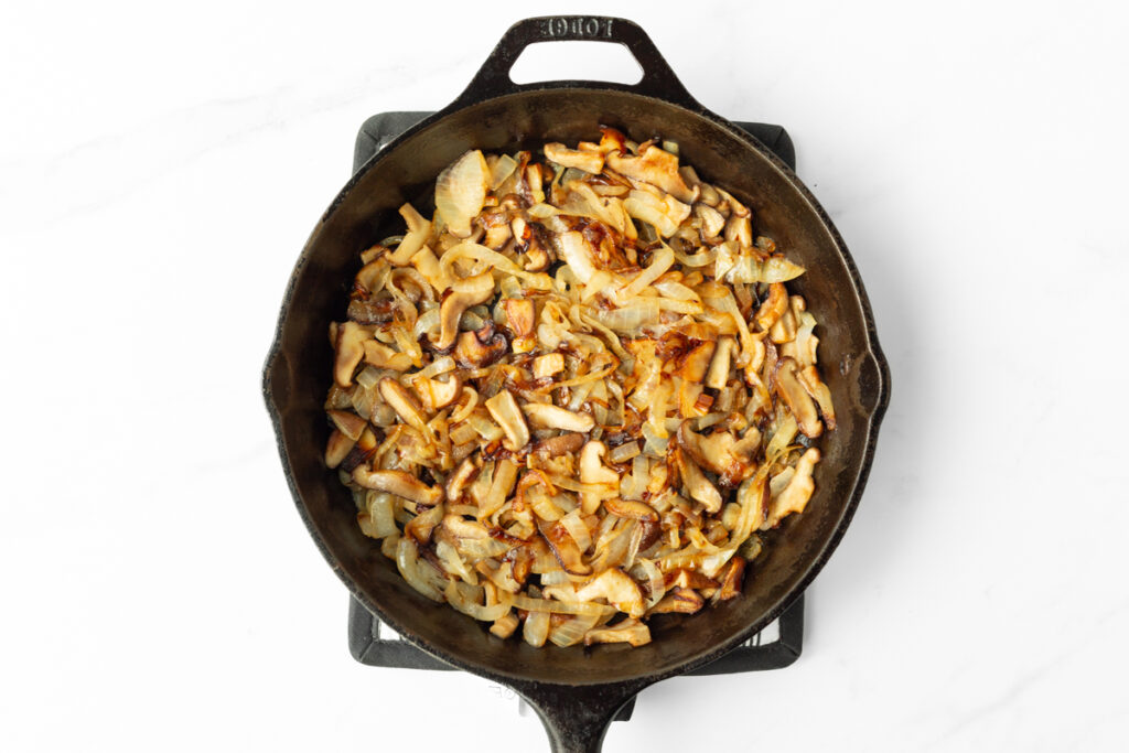 Process shot #1: Caramelized shiitake mushrooms and onions in a cast iron pan.