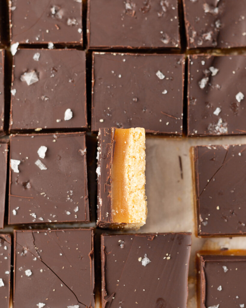 Gluten Free Millionaire's Shortbread with Honey Caramel cut into square bars with one showing the layers.