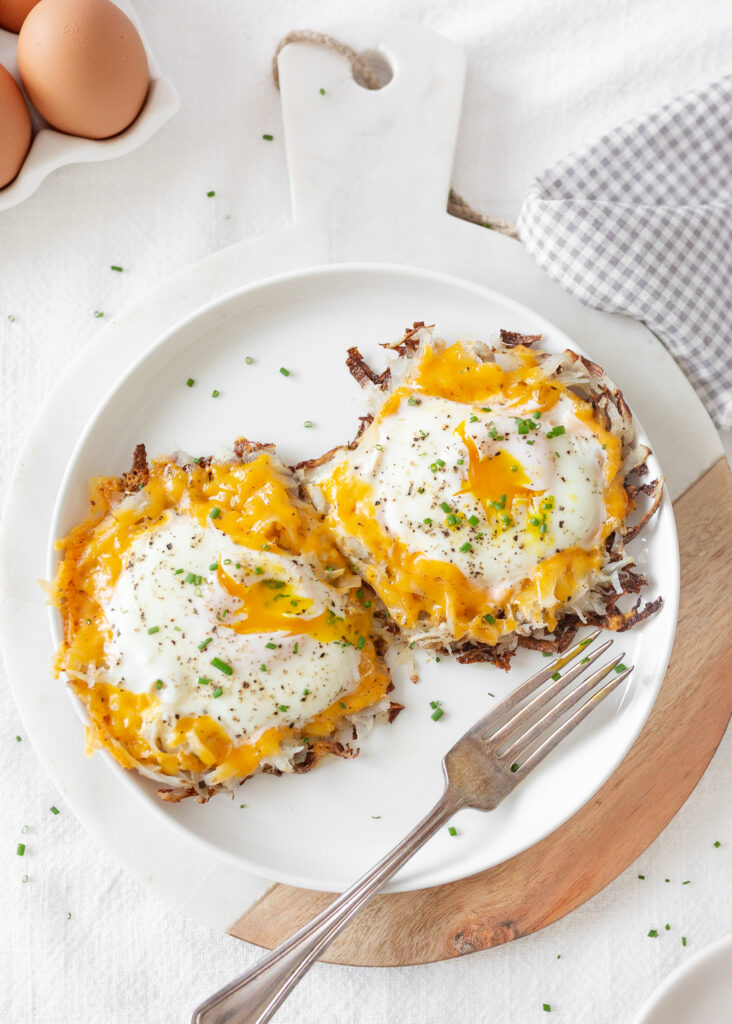 Fried Egg and Potato Nests cooked and served on a plate, topped with fresh chives.