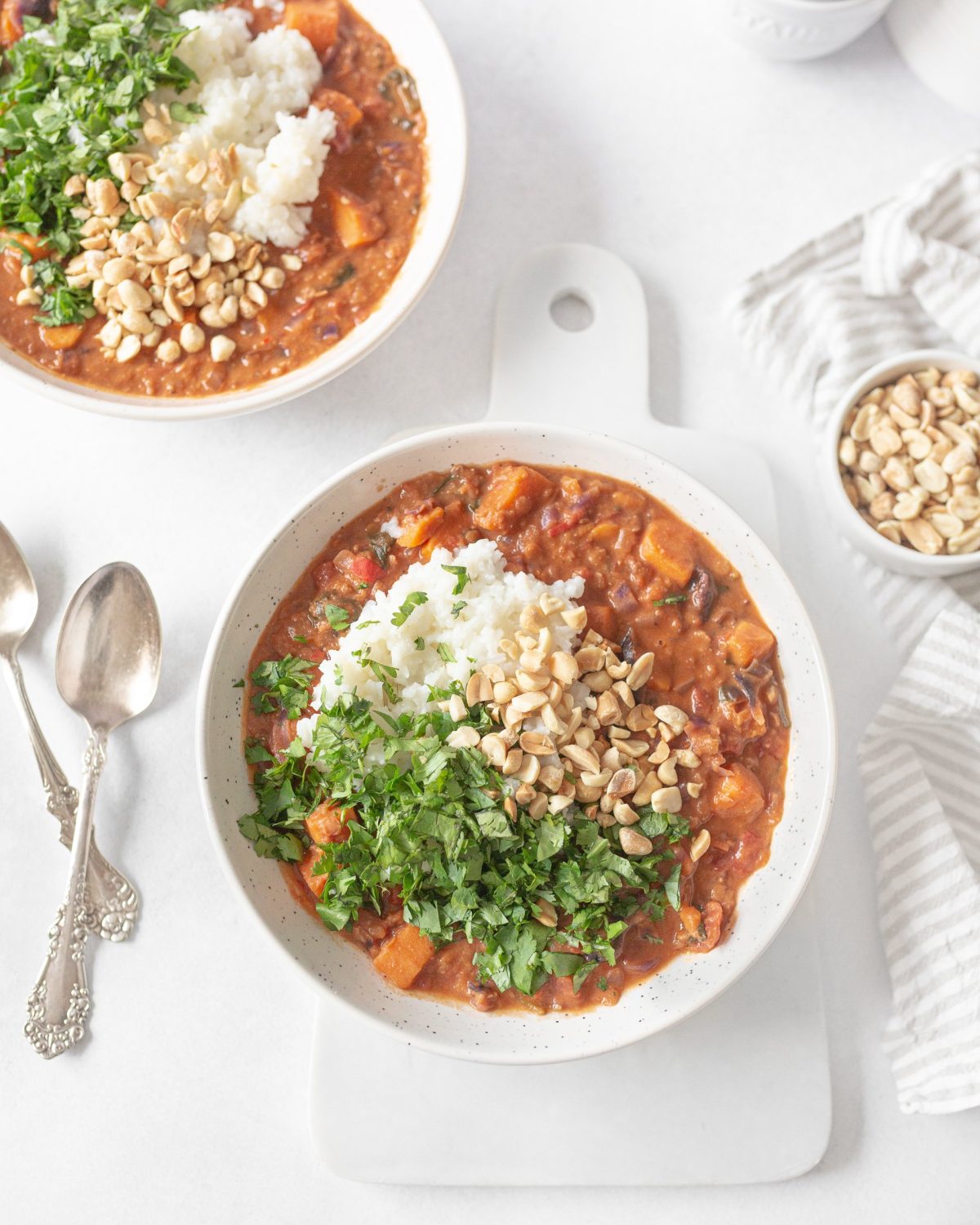 Vegan African Peanut Stew garnished with white basmati rice, fresh cilantro and chopped peanuts.