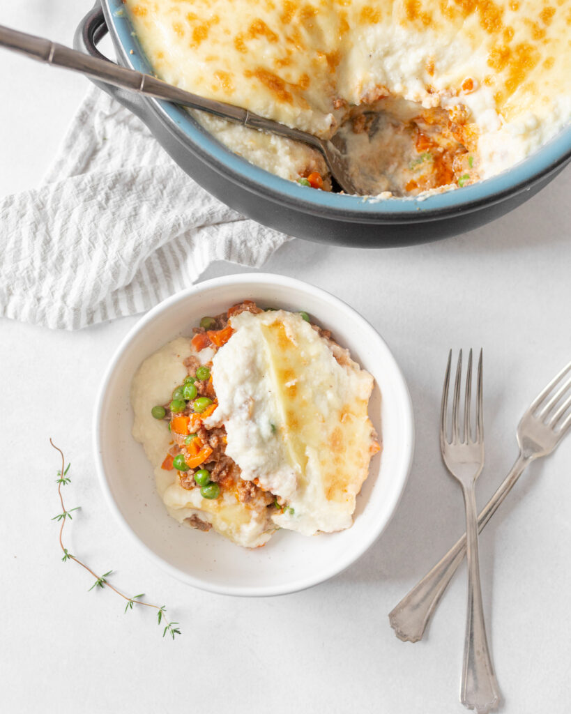Shepherd's Pie with Cauliflower mash served in a bowl with two forks beside it. 