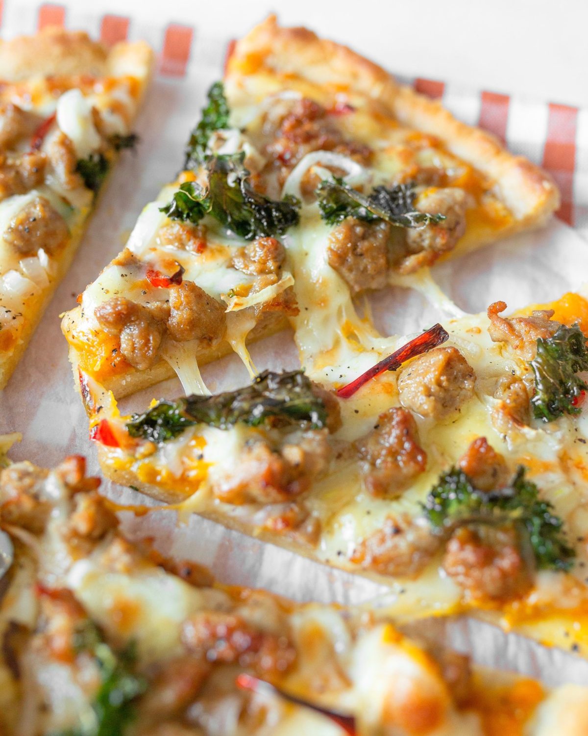 A couple of slices of pizza being pulled apart with stringy cheese between them.
