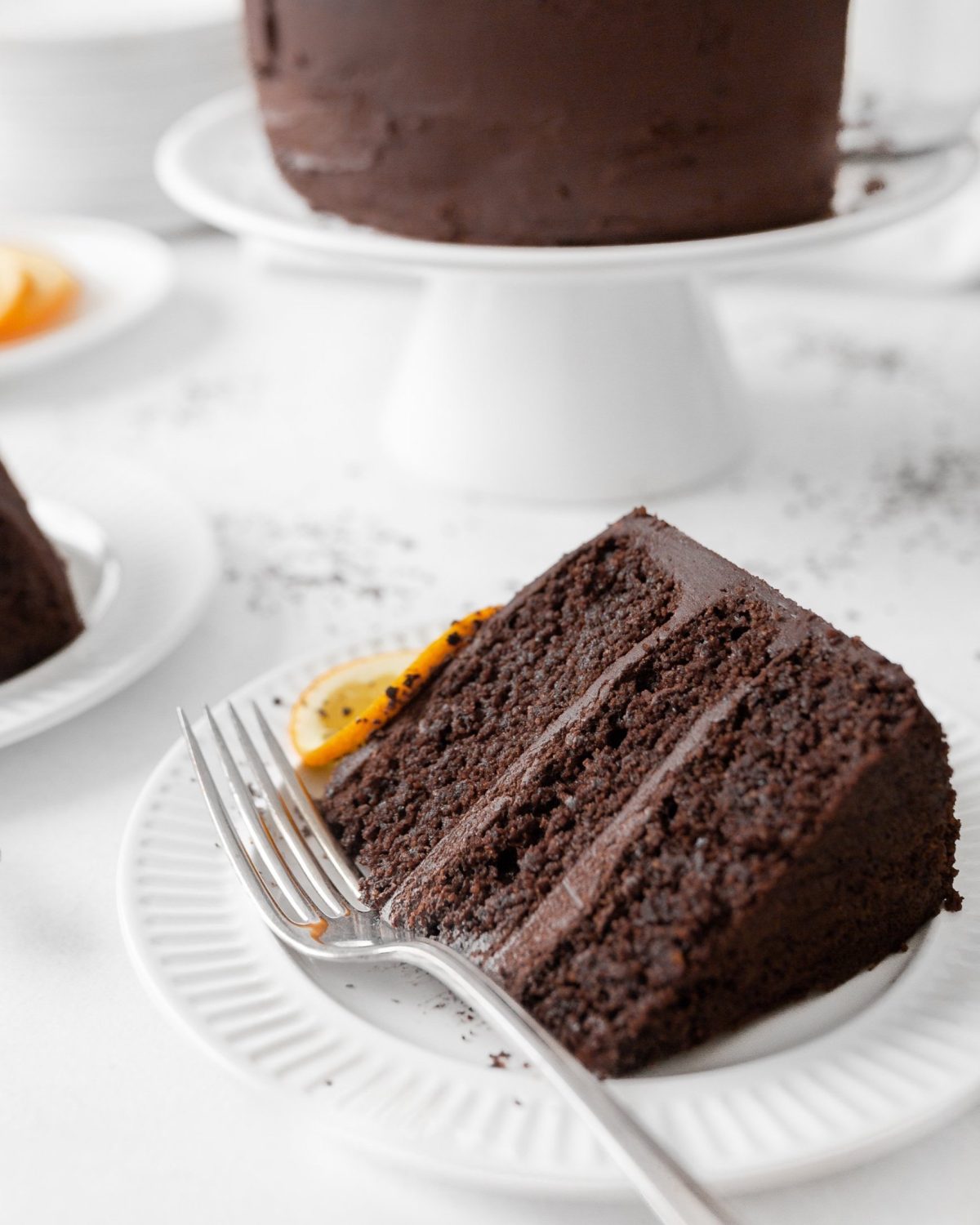 A slice of gluten free Chocolate Orange Cake on a small dessert plate with a fork.