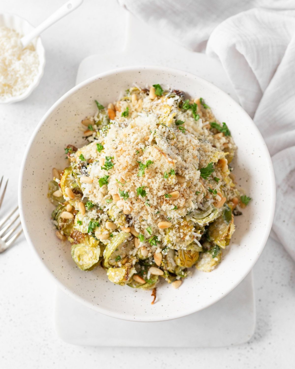 Brussels Caesar Salad with Pine Nuts plated and topped with crispy breadcrumbs and fresh parsley.