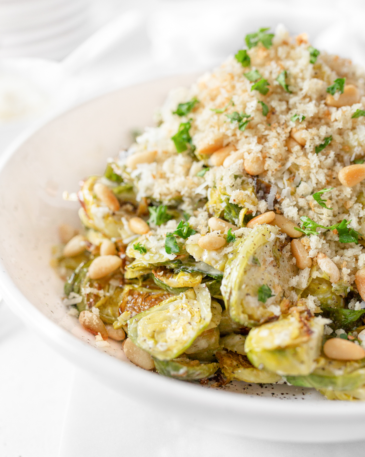Brussels Caesar Salad with Pine Nuts plated and topped with crispy breadcrumbs and fresh parsley.