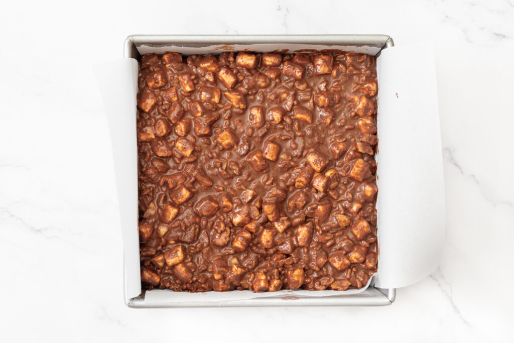 Process shot #4: Rocky road bars mixture transferred to a parchment-lined, 8"x8" square baking pan ready to be chilled in the fridge.
