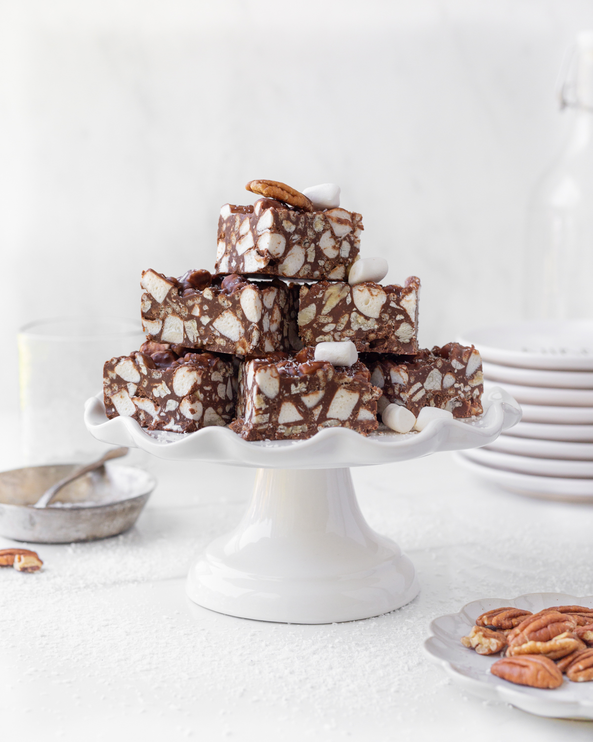 Rocky Road Bars piled on top of a small white ceramic cake stand.