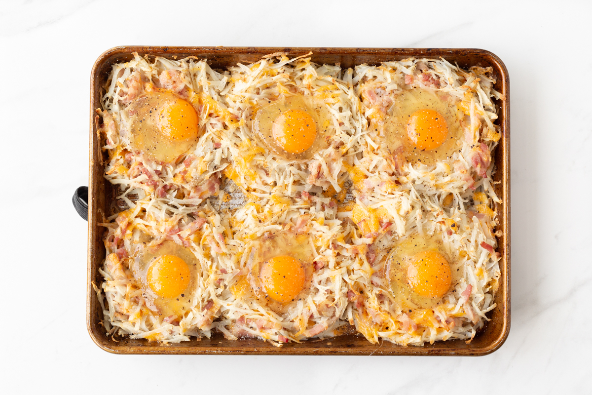 Process Shot #5: Sheet Pan Breakfast Nests partially baked with raw eggs added to the centres of each of them.