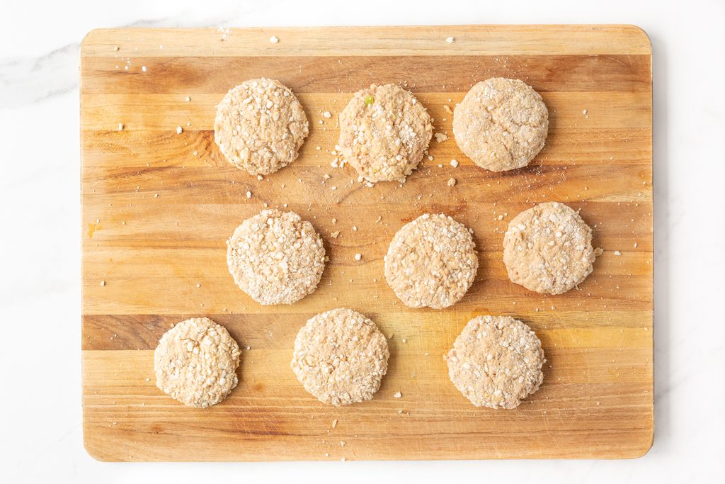 Process shot #3: Breaded tuna cakes uncooked on a wooden cutting board.