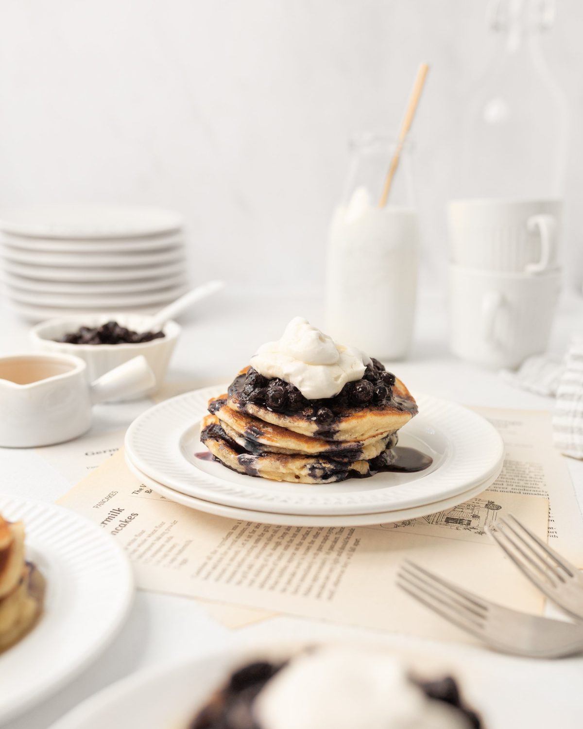 3 Gluten Free Blueberry Pancakes stacked on a plate topped with whipped cream.