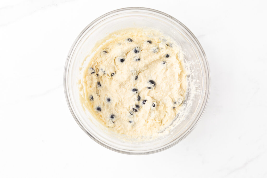 Process shot #3: Gluten free pancake batter with fresh blueberries in a glass mixing bowl.