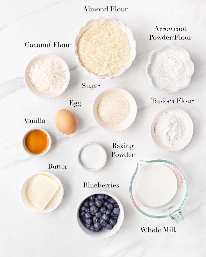 Ingredients for gluten free blueberry pancakes portioned out on a marble slab.