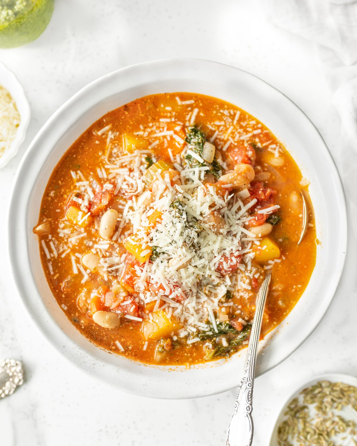 White Bean Minestrone Soup in a bowl, garnished with parmesan cheese.