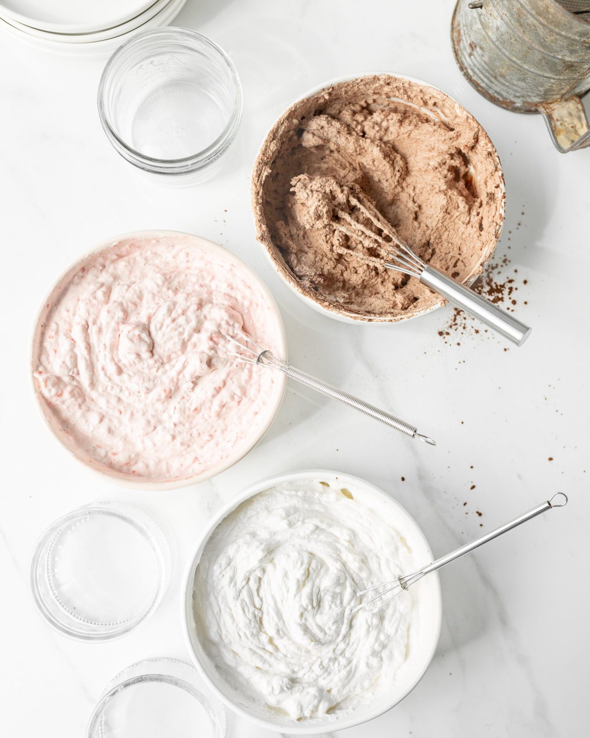 Chocolate, strawberry and vanilla mousse whisked in separate bowls.