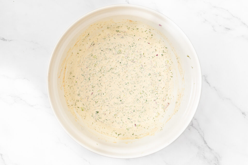 Process shot #3: Creamy herb dressing, chopped pickles. celery, onion, chives and dill mixed in a mixing bowl.