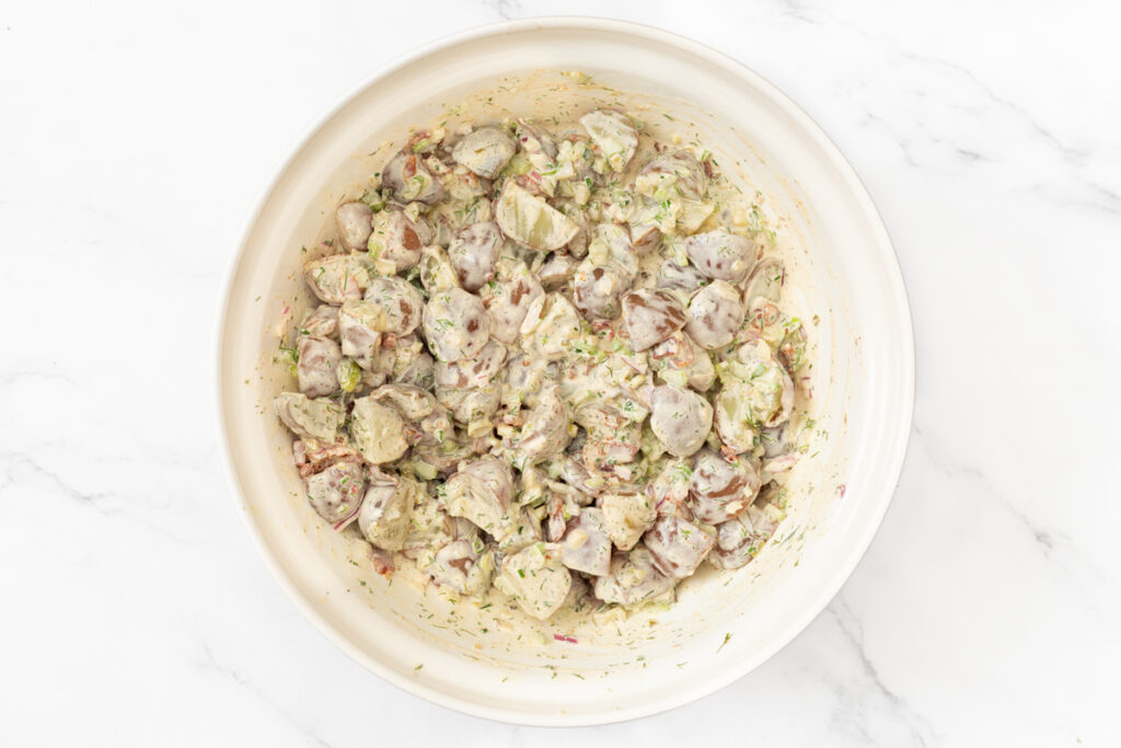 Process shot #4: Potato salad with the dressing mixed together in a large mixing bowl.