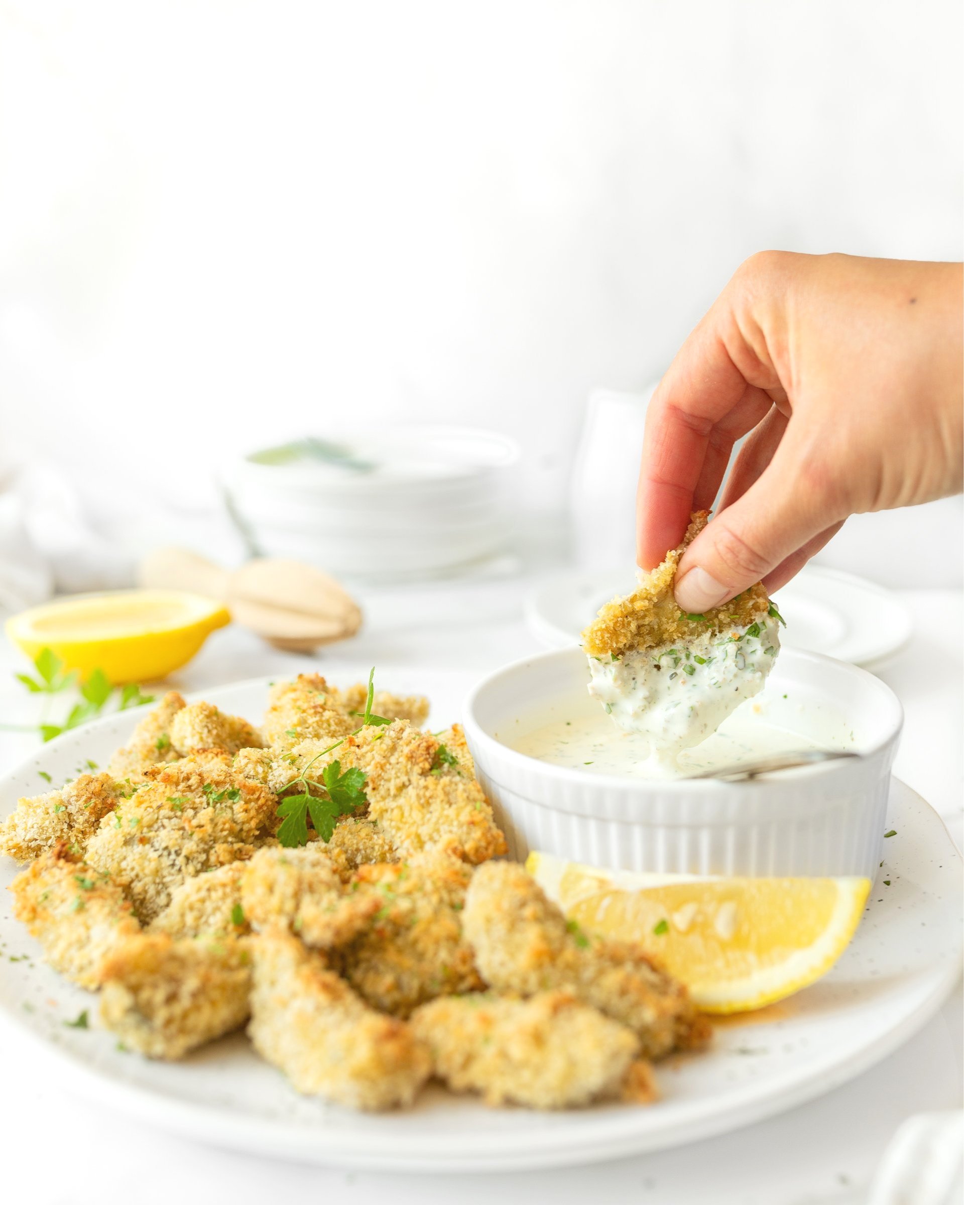 Crispy Oven-baked Artichoke Hearts with Lemon Herb Dip plated and garnished with fresh parsley.