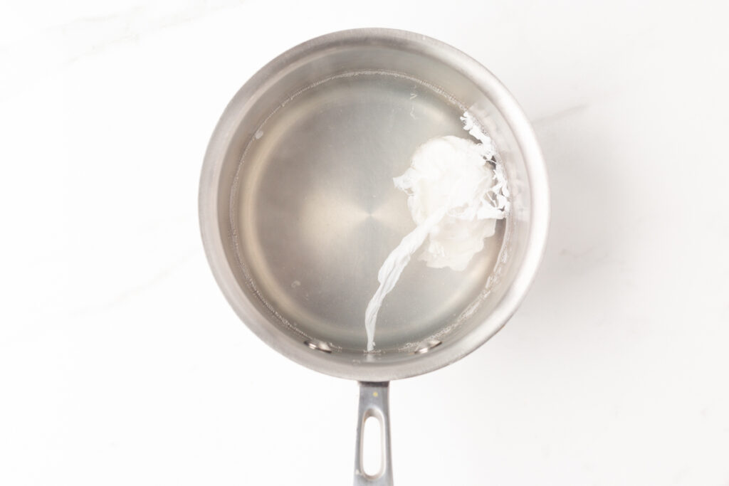 Process shot #3: a single poached egg in a small saucepan.
