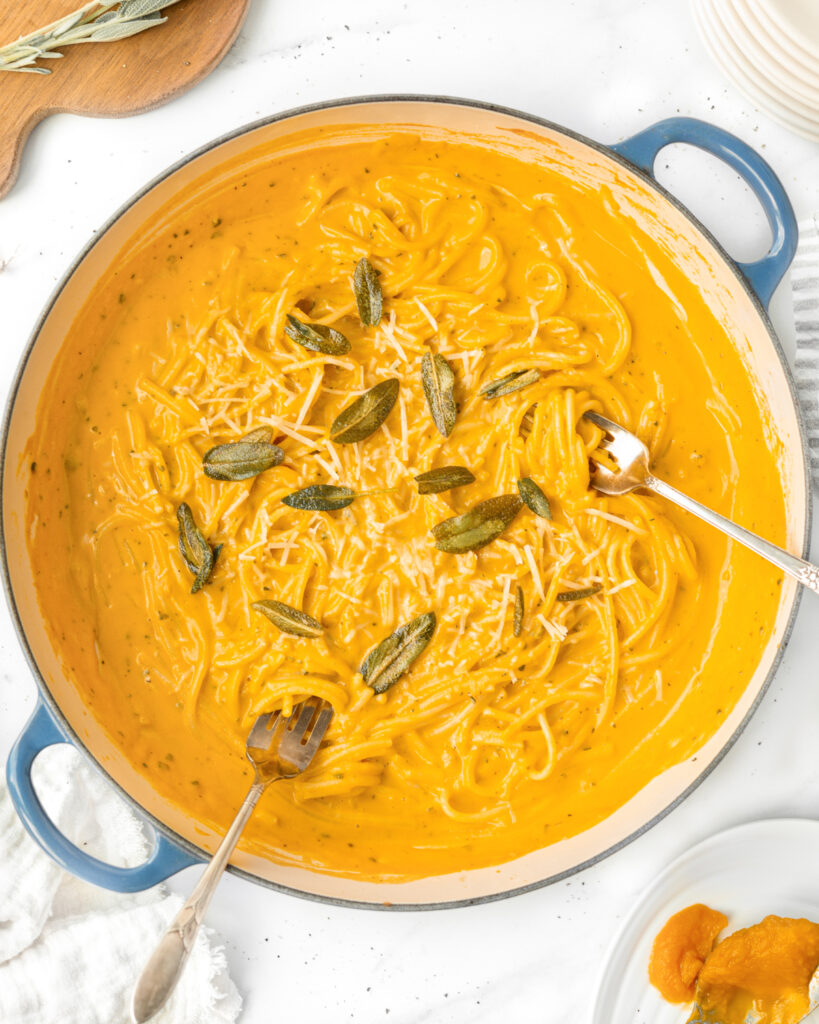 Creamy Pumpkin Pasta cooked and mixed in a pan and garnished with fresh sage.