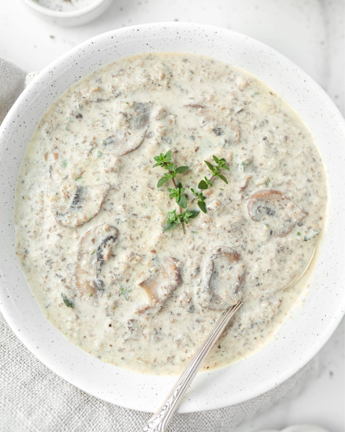 Creamy GF Mushroom and Thyme Soup in a bowl, garnished with fresh thyme.
