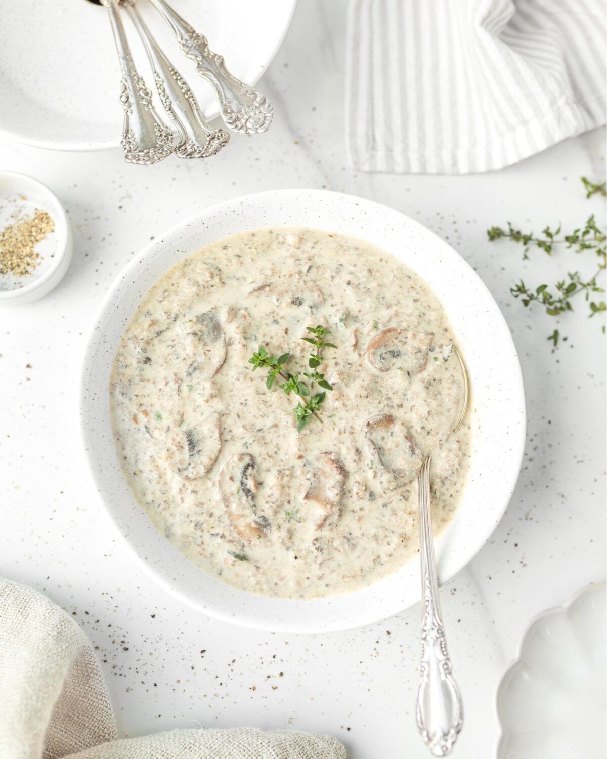 Creamy Gluten Free Mushroom and Thyme Soup in a bowl, garnished with thyme.