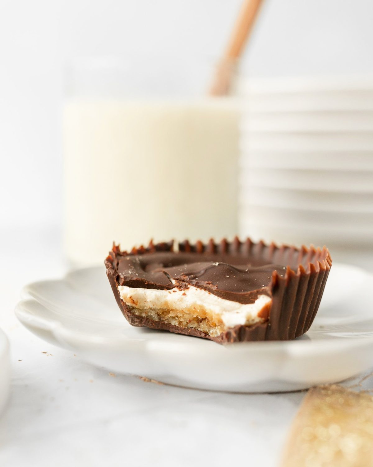 A single Gluten Free Chocolate-covered Egg Nog Cheesecake Bite on a small plate with a bite taken out of it.