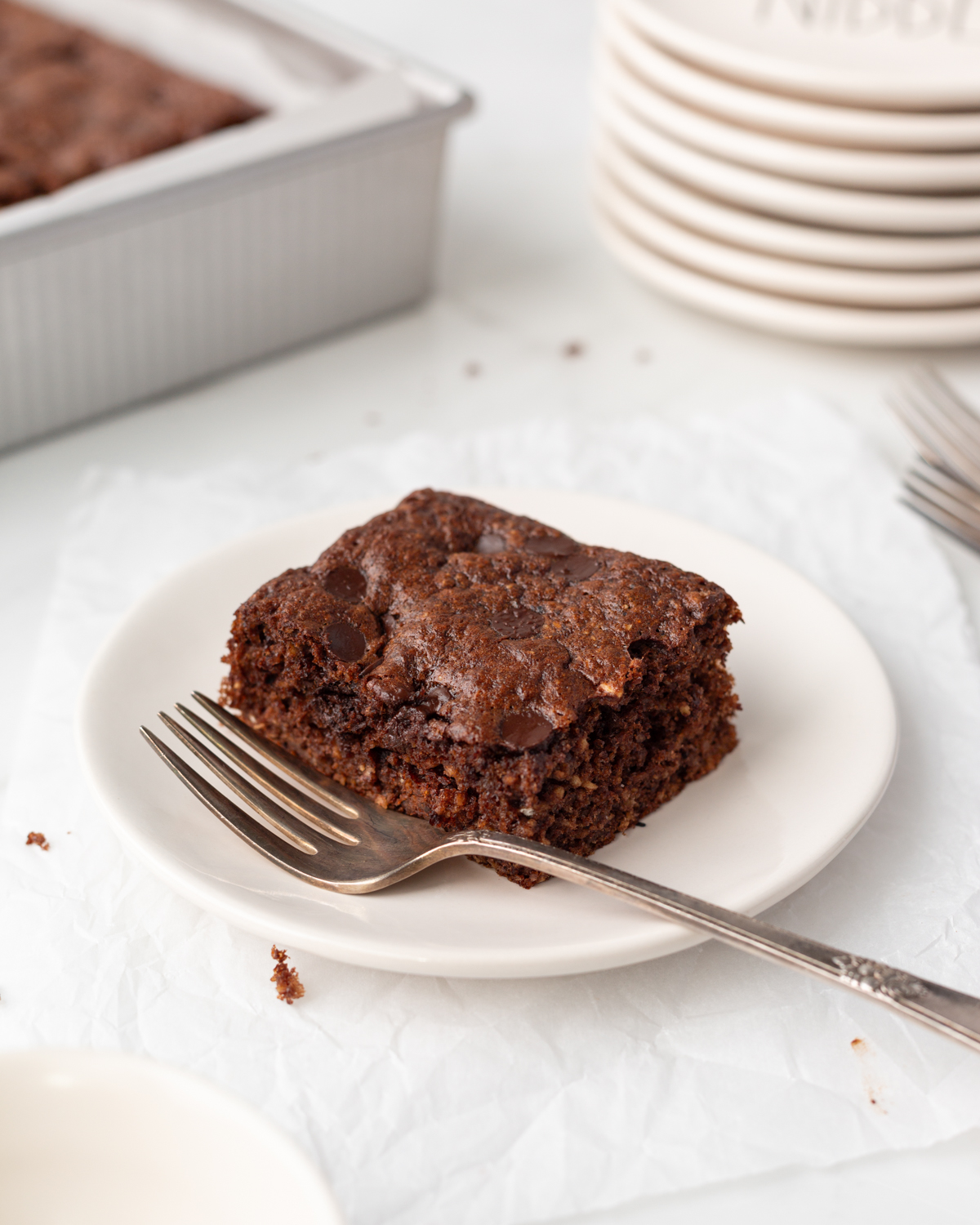 A square of Chocolate Banana Protein Cake cut on a small plate with a fork.