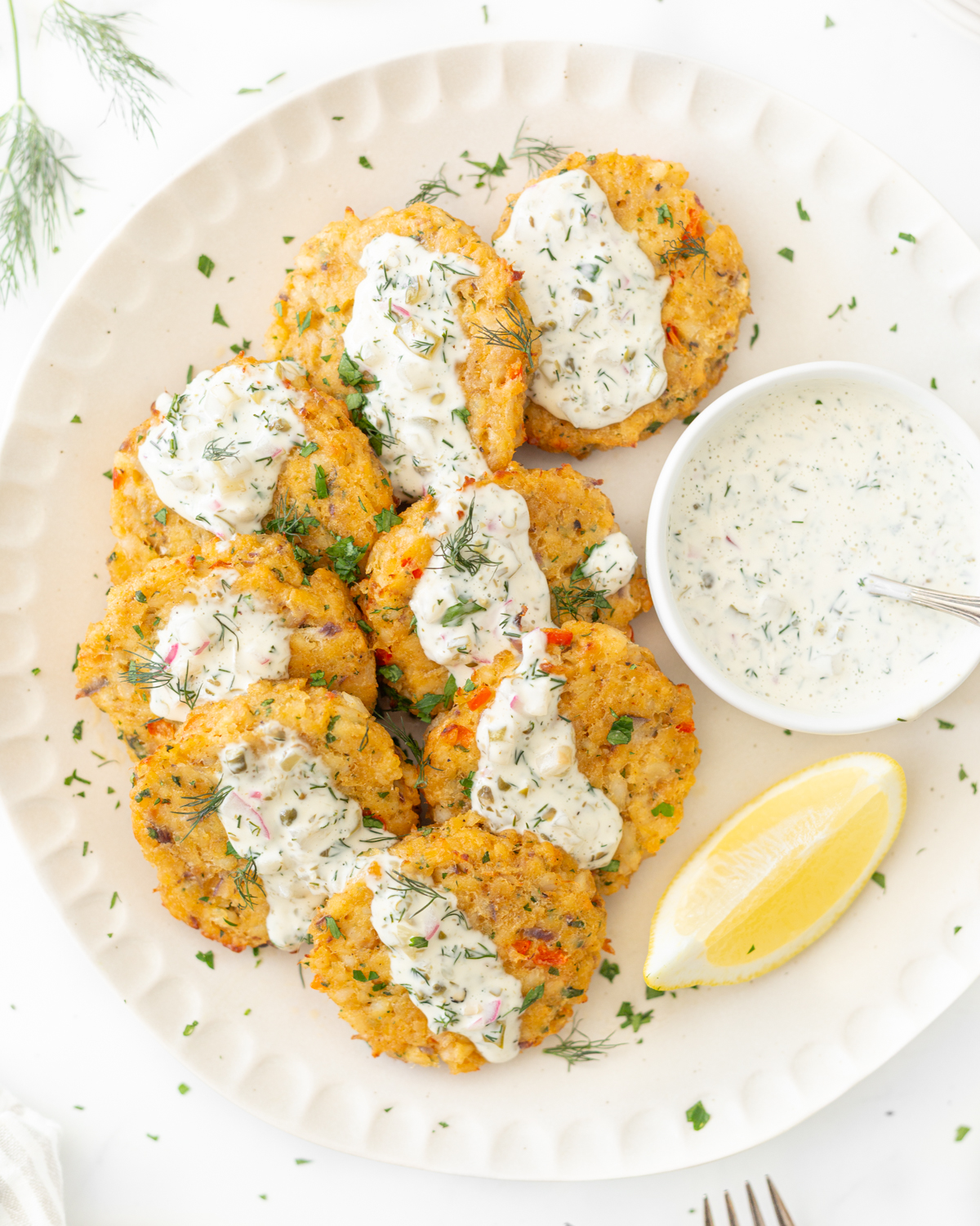 Air Fryer Cod Cakes plated and topped with homemade tartar sauce and fresh dill.