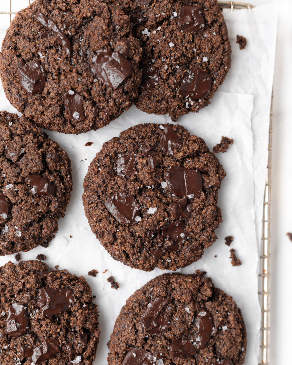 Gluten Free Double Chocolate Cookies baked on parchment paper and topped with flakey sea salt.