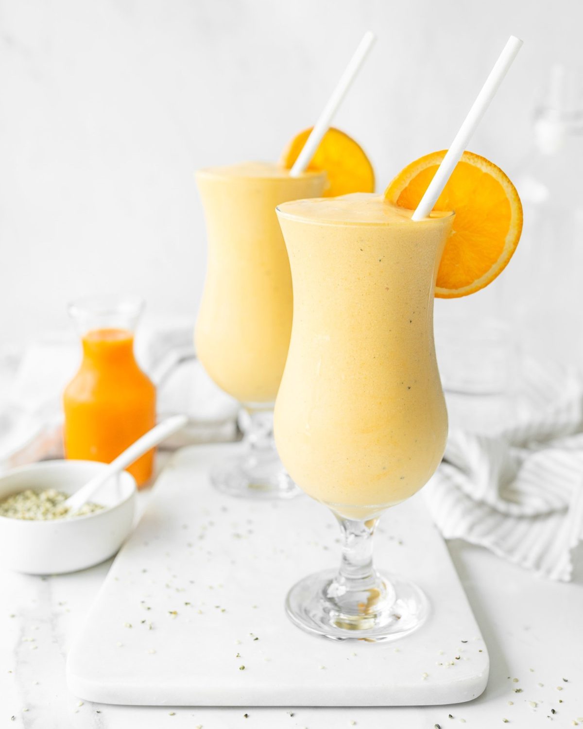 Vegan Mango Turmeric Smoothies in tall glasses with straws.