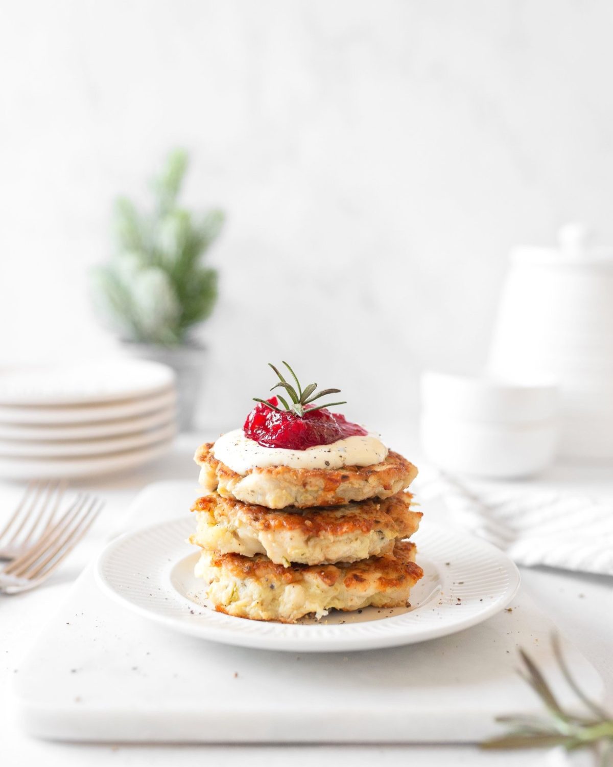 3 Chicken Fritters with Garlic Rosemary Aioli and Cranberry Sauce stacked on a plate.